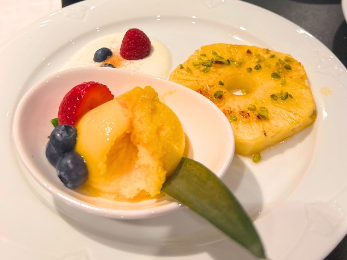 Dessert mit Mangosorbet, karamellisierter Ananas, Beeren und Pistazien im Waidmanns