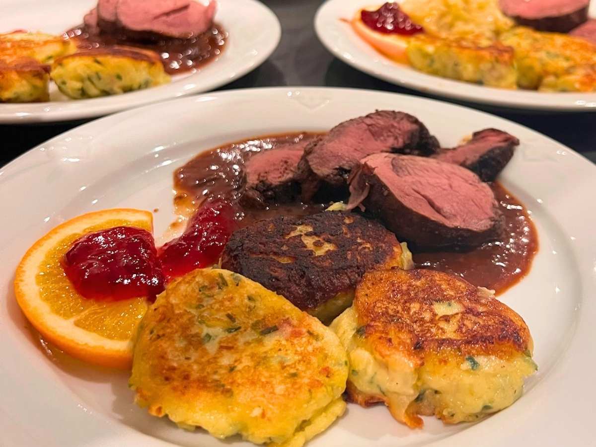 Wildgericht mit rosa gebratenem Fleisch, Sauce, Kartoffelbeilagen und fruchtiger Garnitur im Waidmanns
