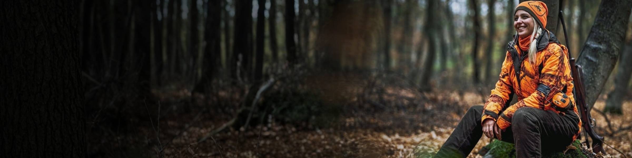 Jägerin in orangefarbener Signalkleidung im Wald
