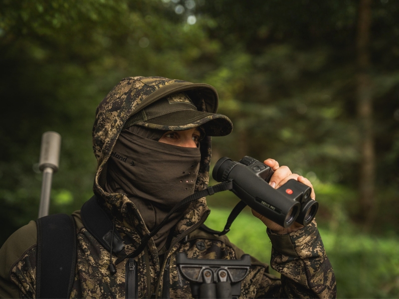 Jäger beobachtet Rehwild mit Fernglas während der Blattjagd
