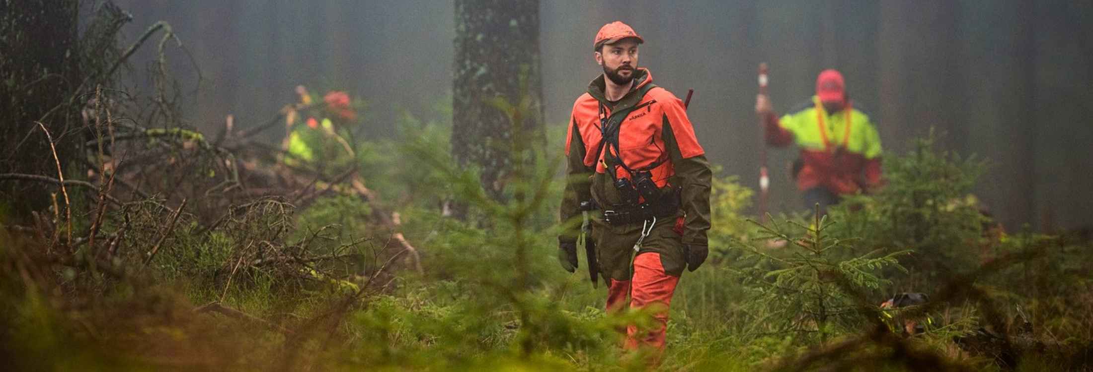 Jäger in Signalbekleidung bei einer Drückjagd im Wald